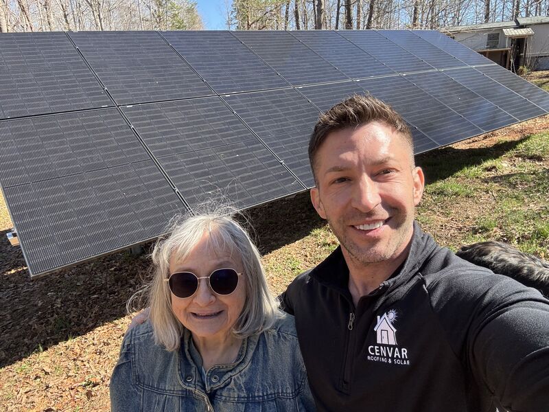 Solar consultant with happy customer in front of ground-mounted solar array